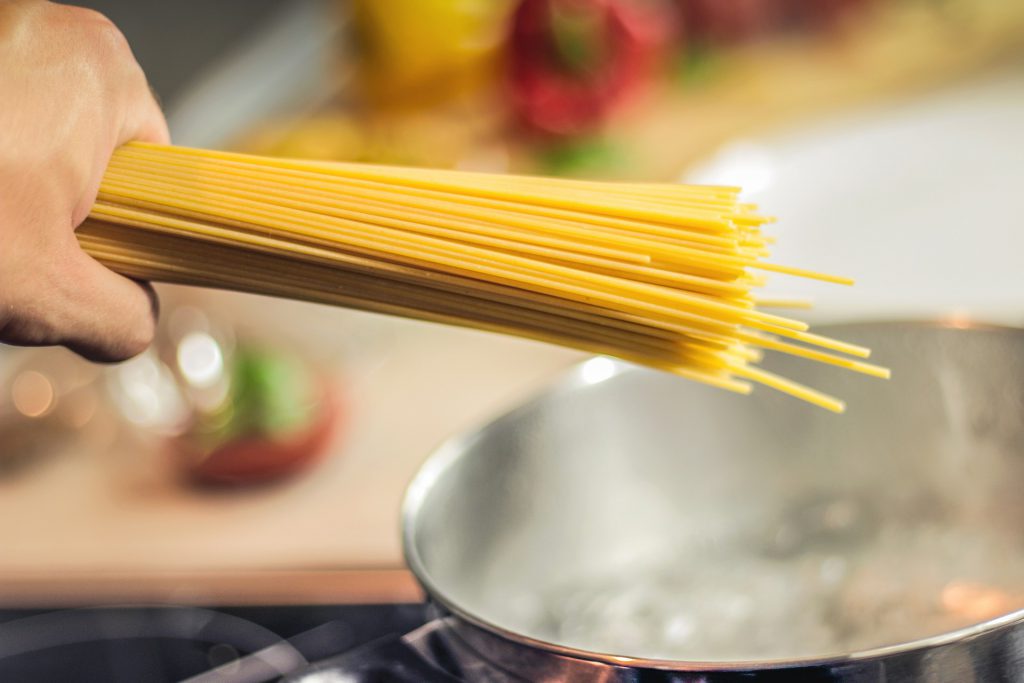 spaghetti going into boiling pot of water