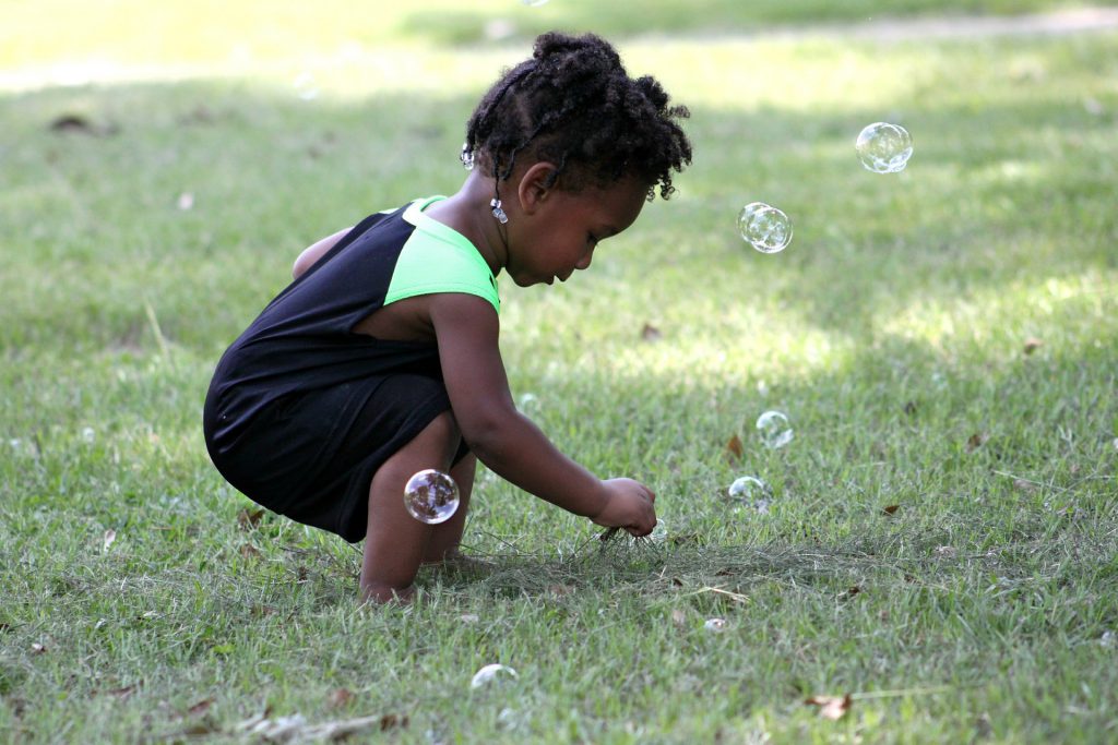child playing outside with bubbles