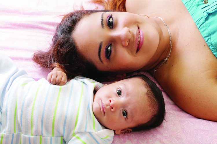 Happy mother lying on bed with child.