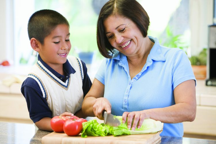 adult cutting lettuce with child watching