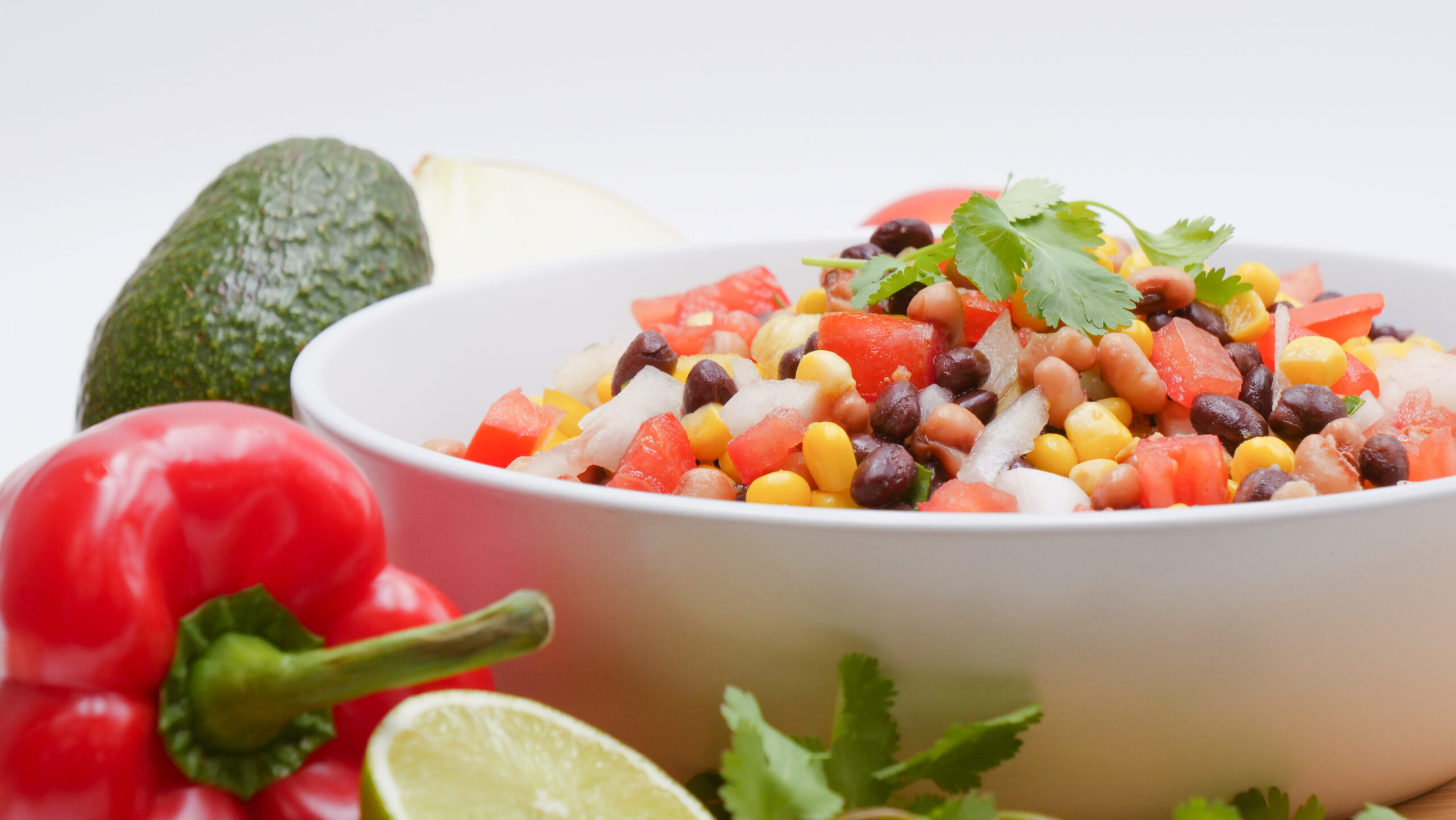 Close up of salsa bowl with vegetables around the bowl.
